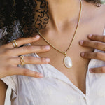 Woman wearing a white dress with gold jewelry outdoors