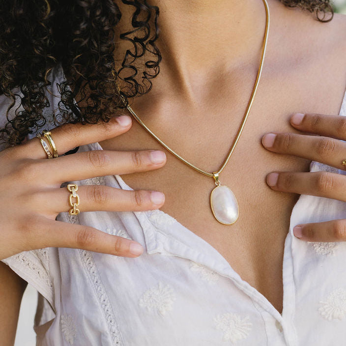 Woman wearing a white dress with gold jewelry outdoors