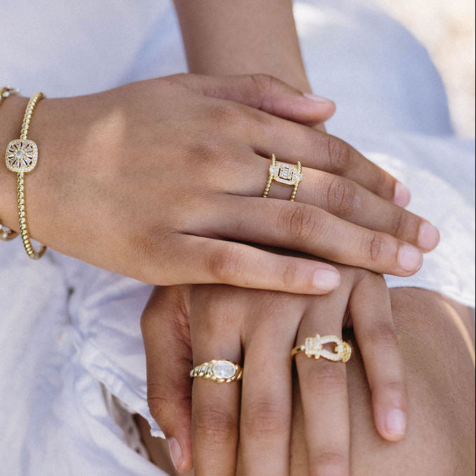 Close-up of hands with gold jewelry on a blurred natural background